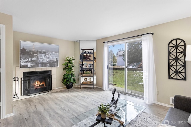 living area with light wood finished floors, a fireplace, and baseboards