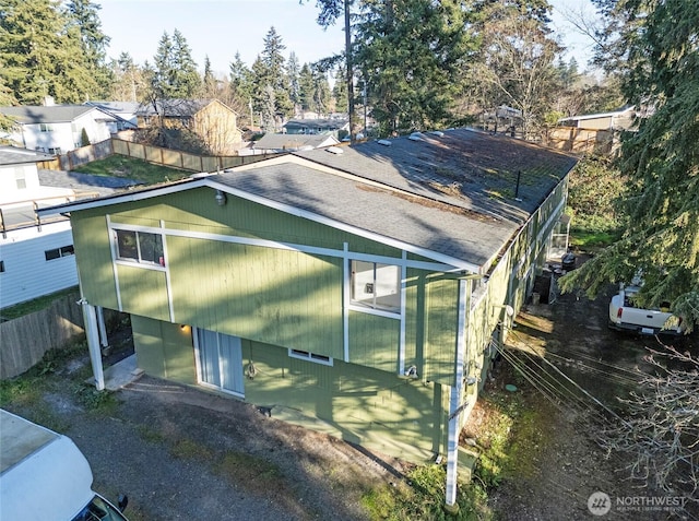 view of home's exterior with a shingled roof and fence