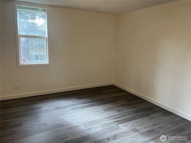 empty room featuring dark wood-style floors and baseboards