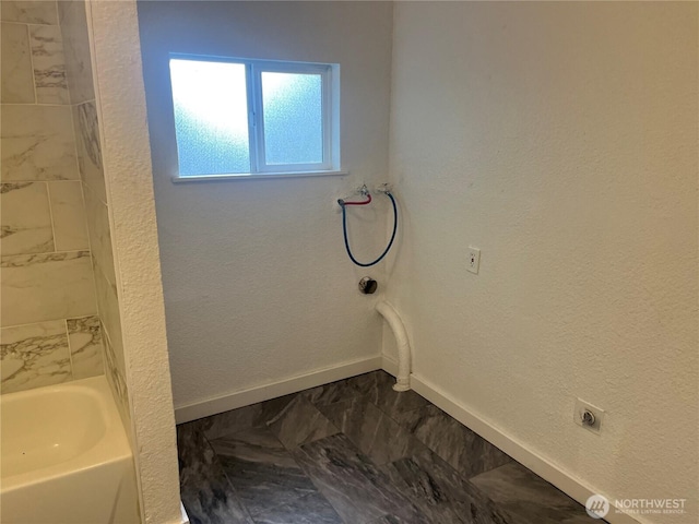 bathroom with a textured wall, marble finish floor, and baseboards