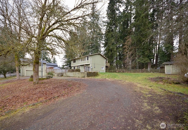 view of front of house featuring driveway, fence, and an outbuilding