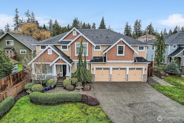 view of front facade featuring a garage, stone siding, driveway, and fence