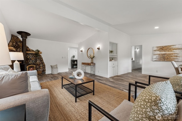 living area featuring baseboards, lofted ceiling, wood finished floors, a wood stove, and recessed lighting