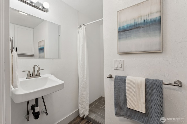 bathroom featuring curtained shower and baseboards