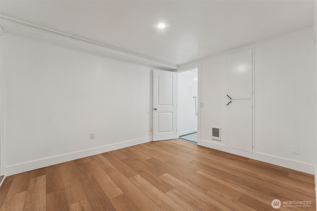 unfurnished room featuring light wood-type flooring, visible vents, and baseboards