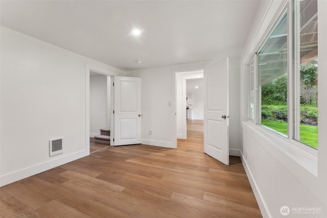 empty room featuring baseboards, stairway, visible vents, and light wood-style floors