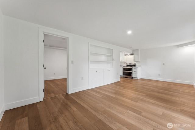 unfurnished living room featuring light wood-style floors, built in features, and baseboards