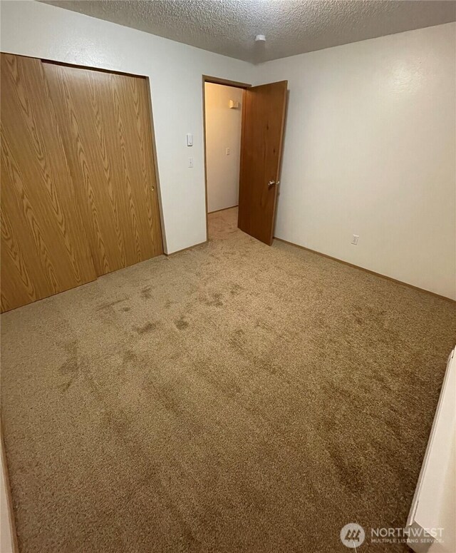 unfurnished bedroom featuring a closet, carpet flooring, and a textured ceiling