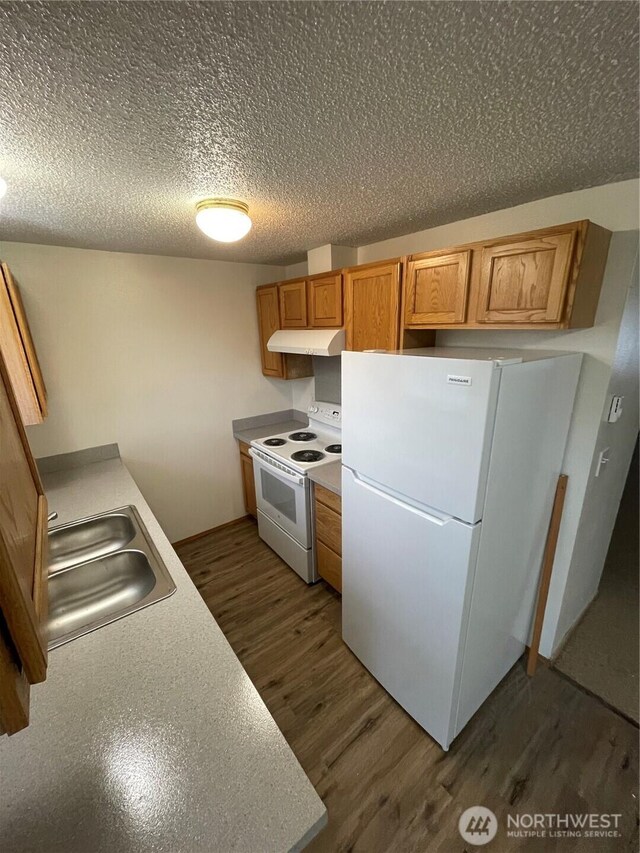 kitchen featuring white appliances, brown cabinets, light countertops, under cabinet range hood, and a sink