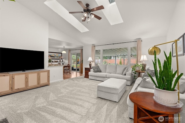 living area with light carpet, high vaulted ceiling, a skylight, baseboards, and ceiling fan