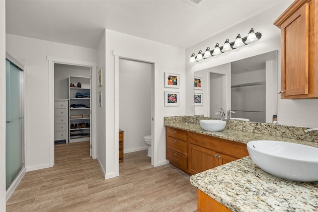 bathroom featuring a sink, double vanity, wood finished floors, and a shower stall