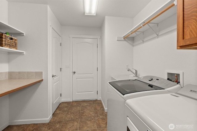 laundry area with a sink, baseboards, cabinet space, and washing machine and dryer