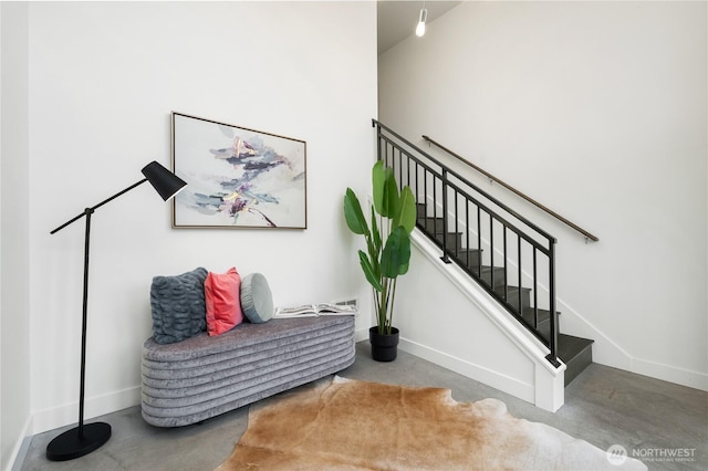 staircase featuring baseboards and finished concrete floors