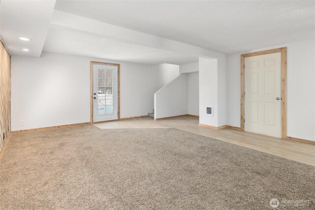 interior space featuring a textured ceiling, recessed lighting, light colored carpet, visible vents, and baseboards