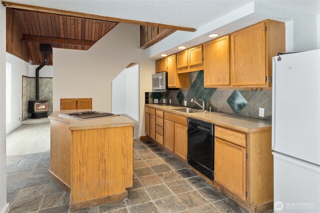 kitchen with stainless steel appliances, light countertops, decorative backsplash, stone finish flooring, and a sink