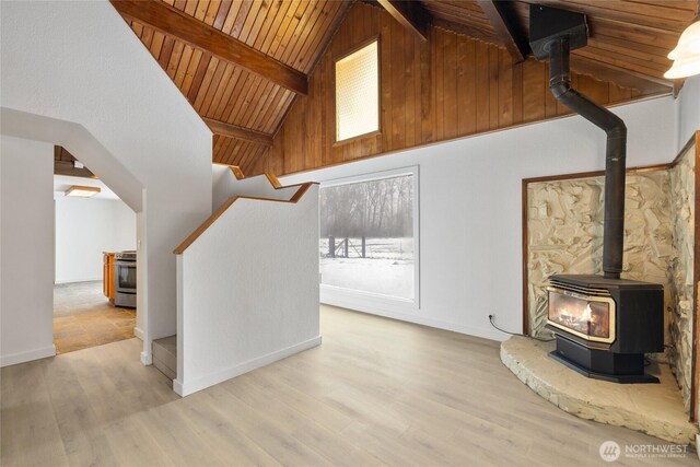 additional living space featuring a wealth of natural light, a wood stove, beamed ceiling, and light wood finished floors