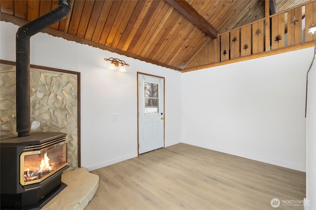 living area with vaulted ceiling with beams, light wood-style floors, wood ceiling, a wood stove, and baseboards