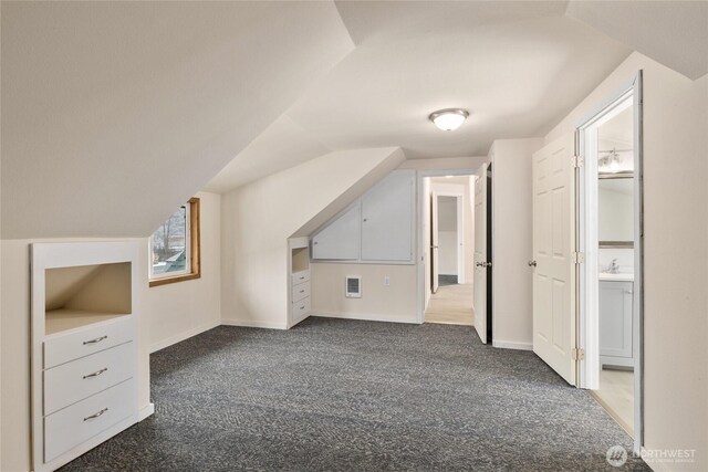 bonus room featuring dark carpet, baseboards, and vaulted ceiling