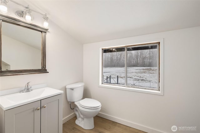 bathroom featuring toilet, vaulted ceiling, vanity, wood finished floors, and baseboards