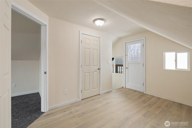 additional living space featuring light wood-type flooring, baseboards, and vaulted ceiling