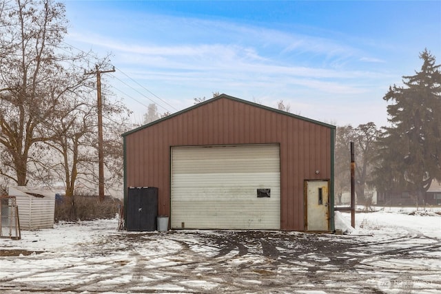 snow covered garage with a detached garage