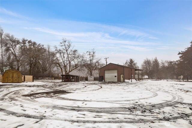 yard covered in snow with a garage and an outbuilding