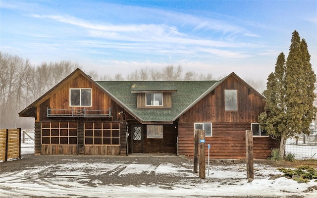 chalet / cabin with a garage, an outdoor structure, an exterior structure, and roof with shingles