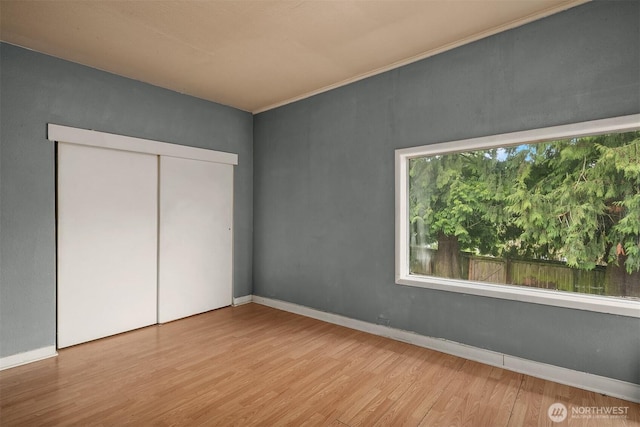 unfurnished bedroom with a closet, baseboards, and wood finished floors