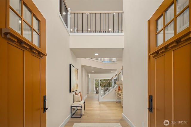 foyer entrance with stairway, baseboards, a high ceiling, light wood-style flooring, and recessed lighting