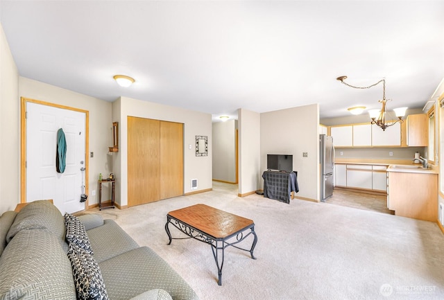 living room featuring light carpet, an inviting chandelier, and baseboards