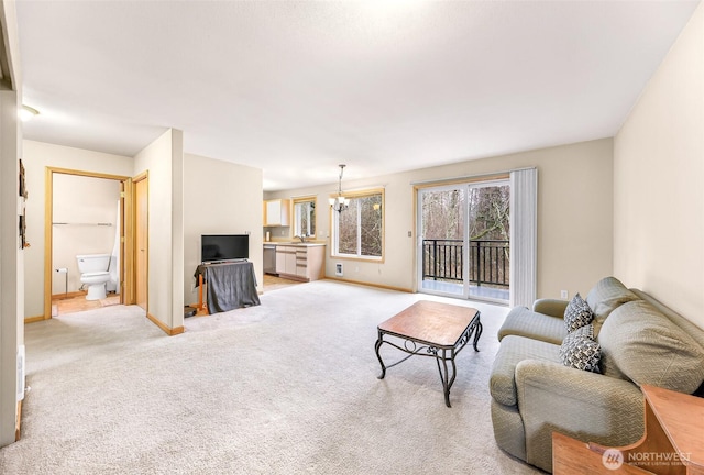 living area featuring light carpet, baseboards, and an inviting chandelier