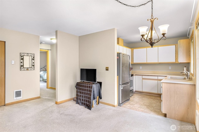 kitchen with decorative light fixtures, stainless steel appliances, visible vents, light countertops, and a sink