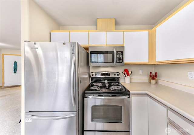 kitchen with carpet, white cabinetry, stainless steel appliances, and light countertops