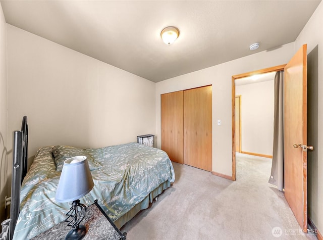 bedroom featuring baseboards, a closet, and light colored carpet