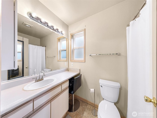 bathroom featuring toilet, baseboards, and vanity