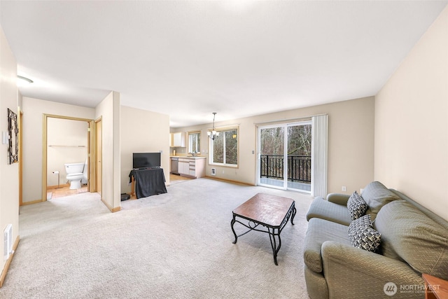 living area featuring light carpet, baseboards, and an inviting chandelier