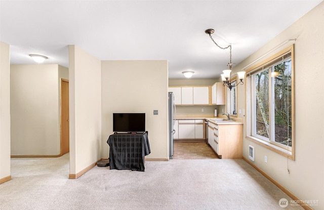 kitchen with pendant lighting, light colored carpet, light countertops, visible vents, and freestanding refrigerator