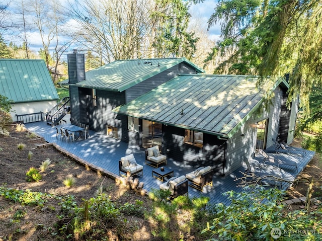 rear view of property featuring a standing seam roof, a chimney, metal roof, and a wooden deck