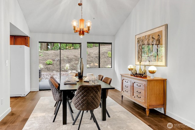 dining area featuring an inviting chandelier, vaulted ceiling, and wood finished floors