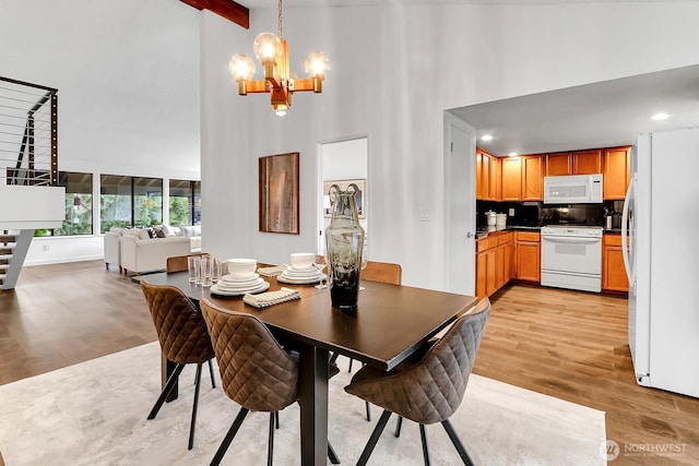 dining space featuring high vaulted ceiling, light wood-type flooring, beam ceiling, and an inviting chandelier