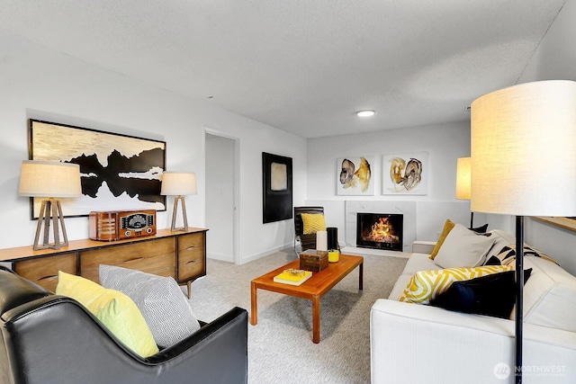 living room featuring carpet floors, a high end fireplace, and baseboards