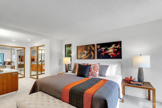 bedroom with baseboards, light colored carpet, a textured ceiling, two closets, and recessed lighting