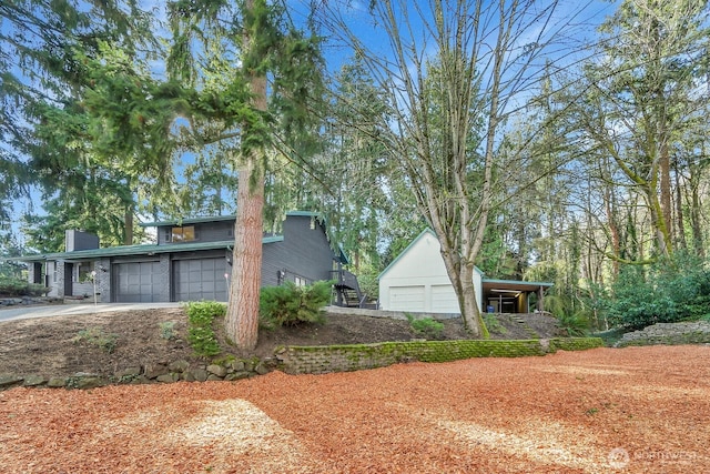 view of side of property featuring a garage, driveway, and a chimney