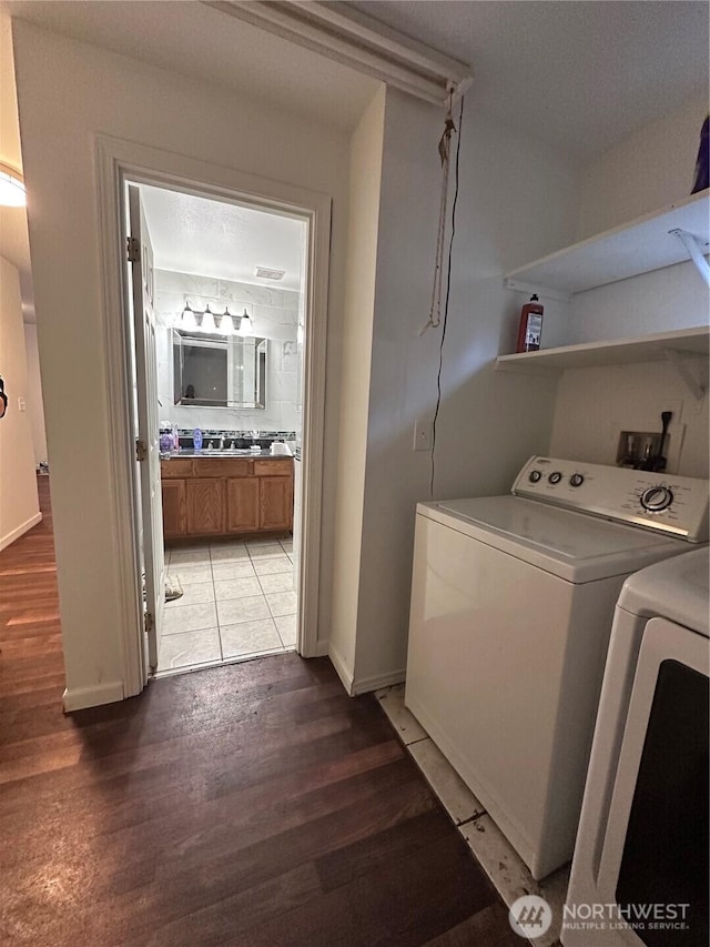 laundry room featuring washer and dryer, baseboards, laundry area, and light wood finished floors