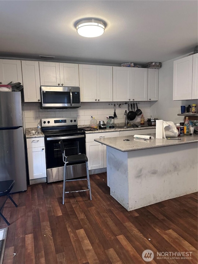 kitchen featuring dark wood-type flooring, tasteful backsplash, appliances with stainless steel finishes, and a sink