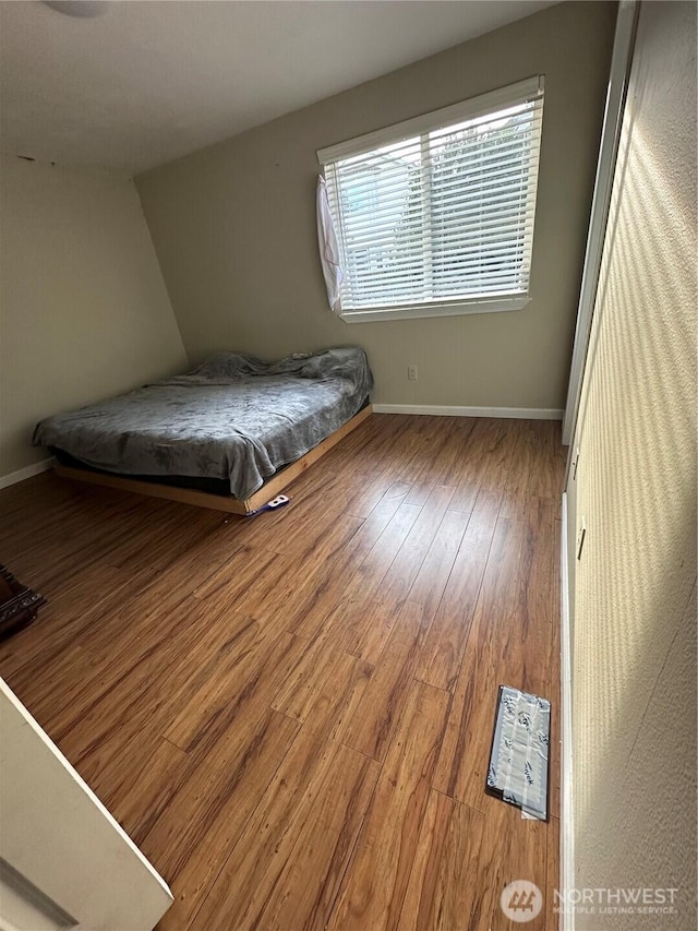 bedroom featuring baseboards, lofted ceiling, and wood finished floors