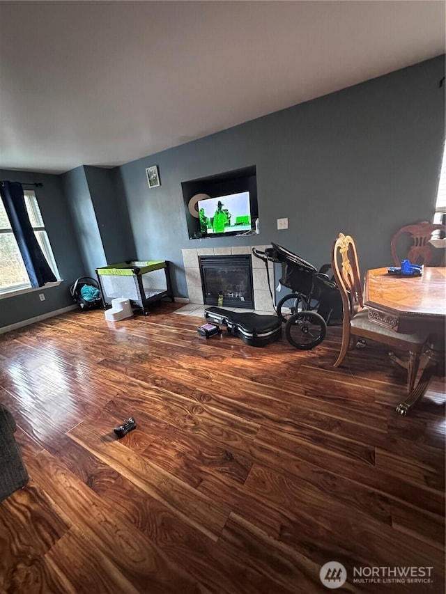 living room with wood finished floors, baseboards, and a tile fireplace