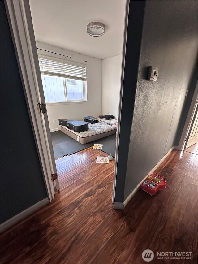 corridor featuring wood finished floors and baseboards