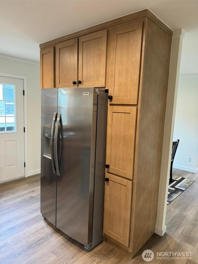 kitchen featuring crown molding, brown cabinetry, light wood-type flooring, and stainless steel fridge with ice dispenser