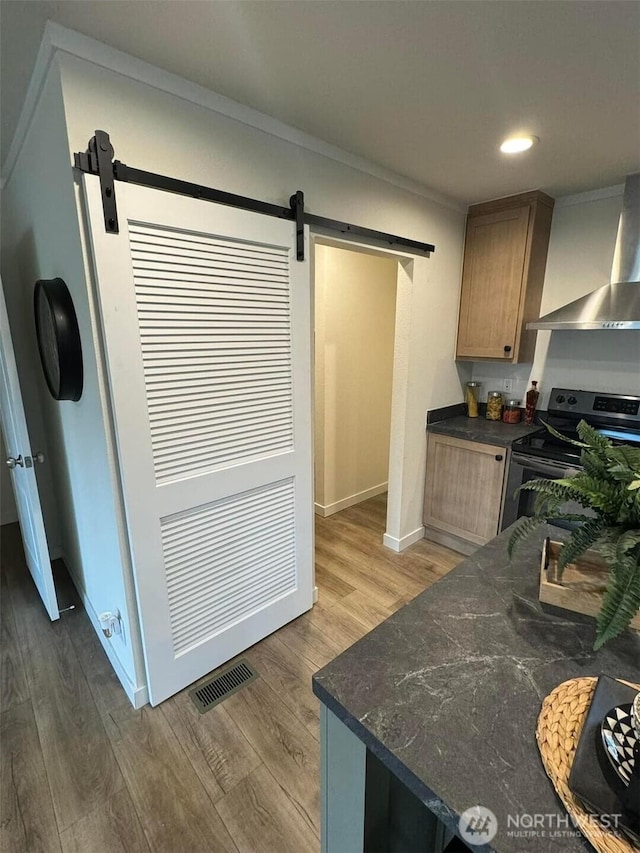 kitchen featuring wall chimney exhaust hood, visible vents, stainless steel electric range, and a barn door